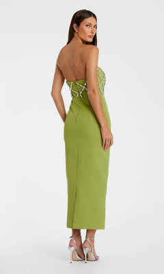A woman in the Mac Duggal 21064 long formal dress, featuring a strapless crepe design with silver crystal embellishments, stands facing away and wears silver high-heeled sandals.