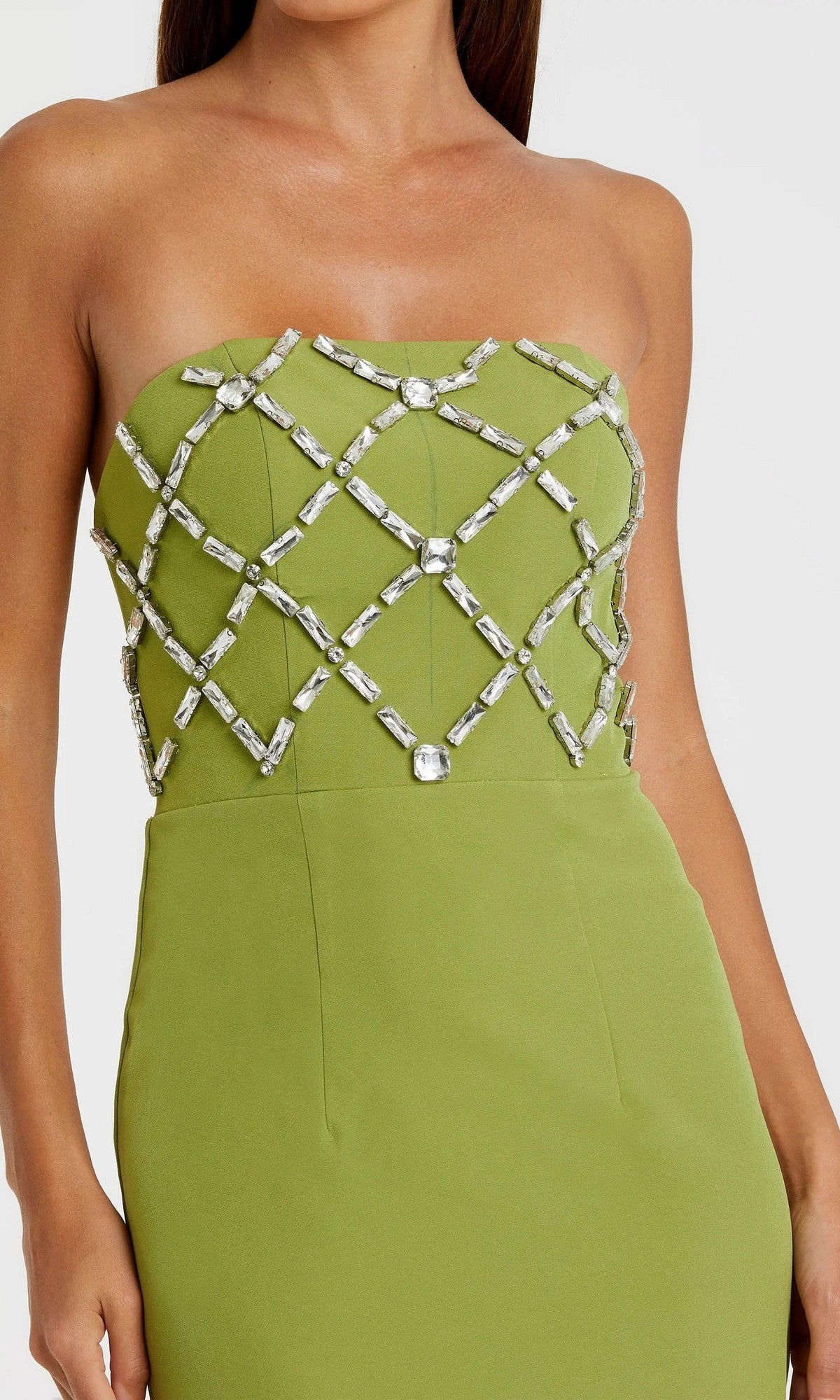 A woman wears the Mac Duggal 21064 long formal dress in green, with a strapless crepe design and striking geometric crystal embellishments on the bodice.