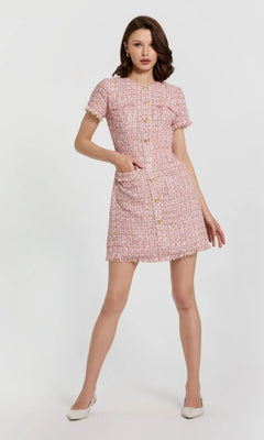 A woman wearing the Short Wedding Guest Dress: Mac Duggal 21072, a pink boucle mini sheath with front buttons, pockets, and high neckline, poses against a plain light background.