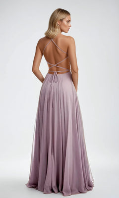A woman wearing the Long Prom Dress: Juliet 210, featuring a lavender backless design with crisscross straps and an elegant A-line skirt, stands facing away from the camera against a plain background.