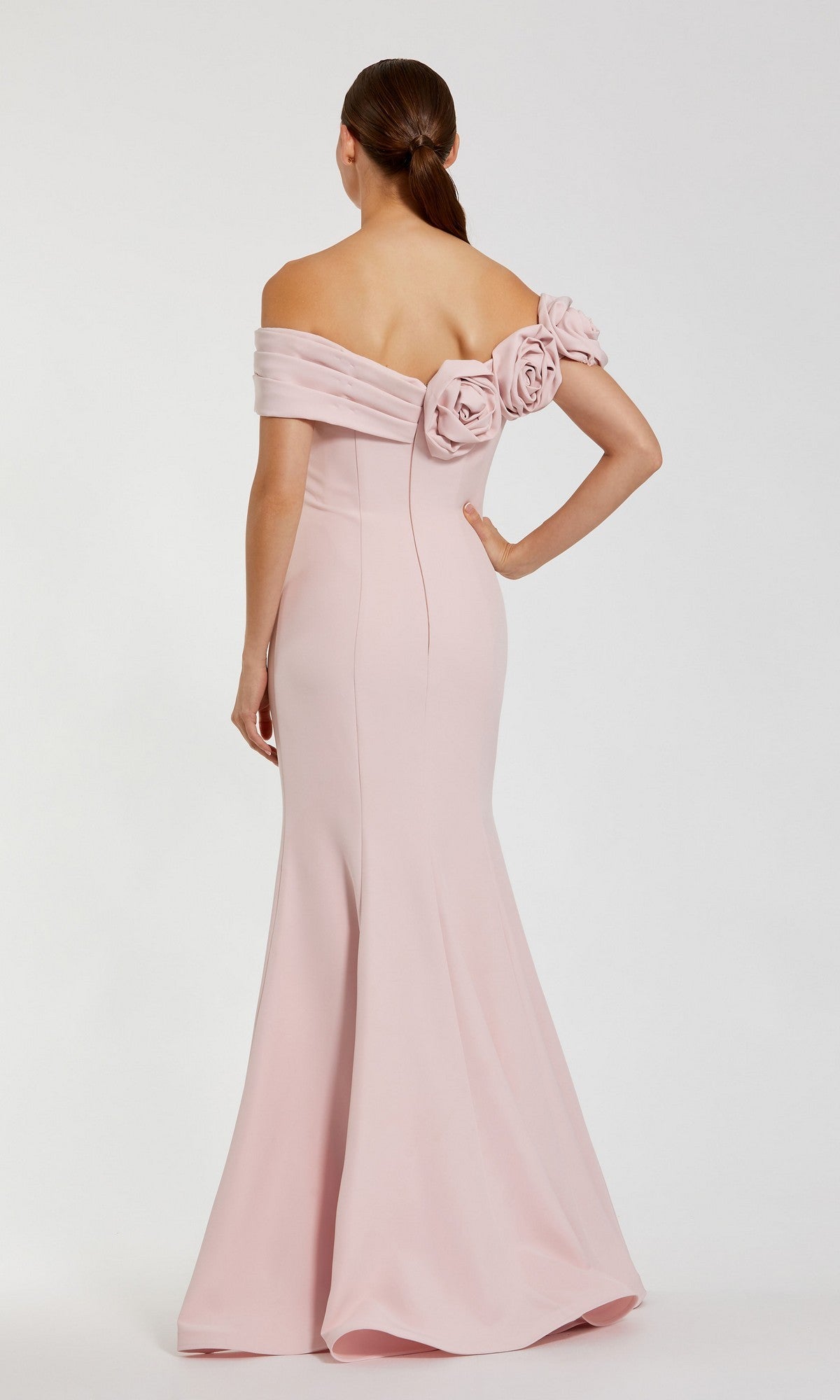 Woman in an off-shoulder Mac Duggal 21104 long formal dress in pale pink with floral detailing on the back stands against a white background, facing away from the camera.