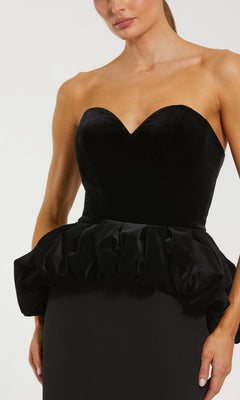 Woman wearing the Mac Duggal 21145 Long Formal Dress, a strapless black velvet gown featuring a sweetheart neckline and ruffled peplum waist detail for an elegant evening look.