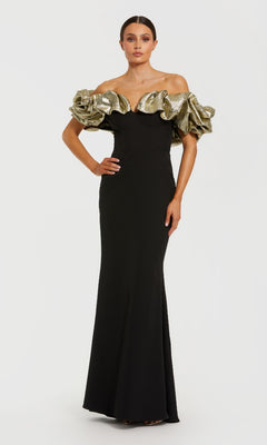 Woman wearing a black evening gown with gold ruffled off-the-shoulder straps standing in front of a white background