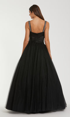 Woman modeling the back of a black ball gown standing in front of a white background