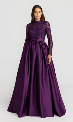 A woman wears the Mac Duggal 21189 long formal dress in aubergine, featuring long sleeves and a beaded-embroidered bodice, standing against a plain light background.