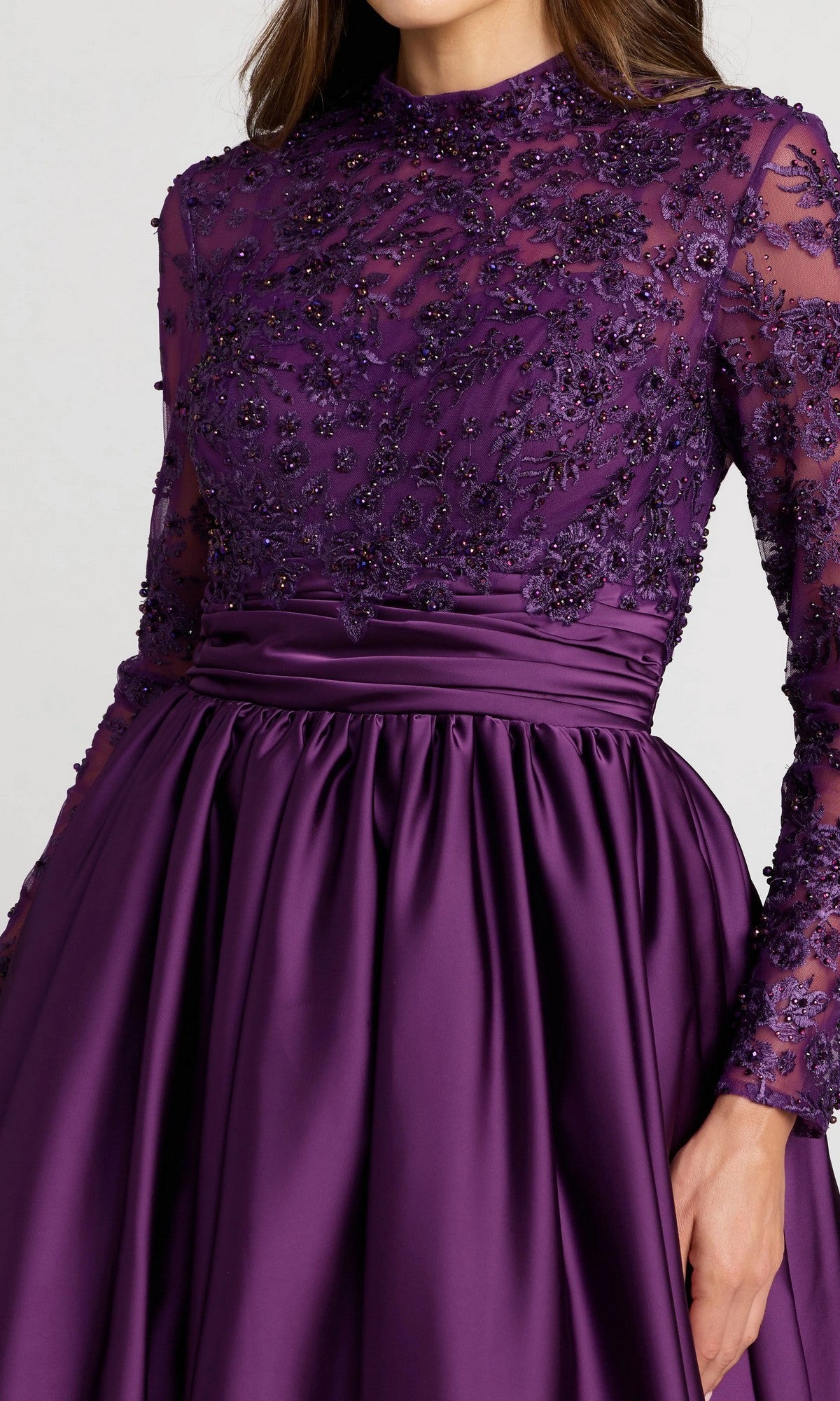 A woman in the Mac Duggal 21189 long formal dress, showcasing a purple design with long sleeves, a beaded-embroidered bodice featuring floral lace, and a flowing satin skirt.