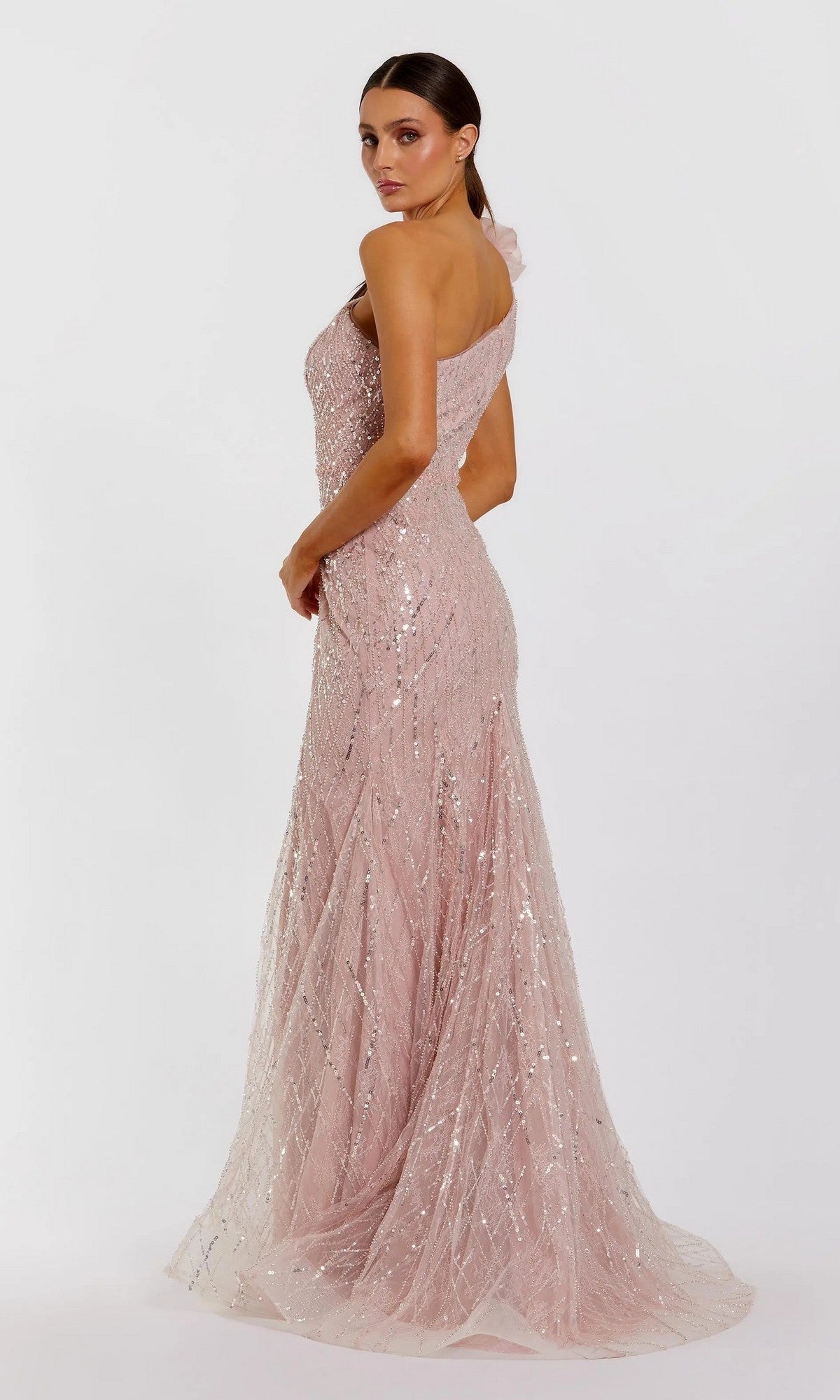 A woman poses in a three-quarter stance against a plain white background, wearing the Mac Duggal 21199 long formal dress—a floor-length, blush pink, one-shoulder sequin gown with elegant detailing that exudes timeless sophistication.
