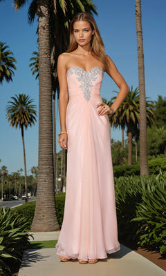 Wearing the La Femme Dress 21214, a woman stands outdoors among palm trees in a strapless light pink gown featuring silver embellishments on its ruched sweetheart bodice.
