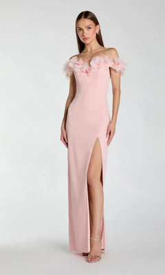 A woman poses against a plain light background wearing the Mac Duggal 21235 long formal dress in dusty rose, featuring an off-shoulder sweetheart neckline with floral applique, a thigh-high slit, and paired with nude heels.