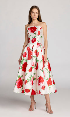 A woman wearing the Mac Duggal 21238 tea-length party dress in Rose Multi, featuring a strapless neckline and bold red rose print, paired with silver strappy heels, stands against a plain background.