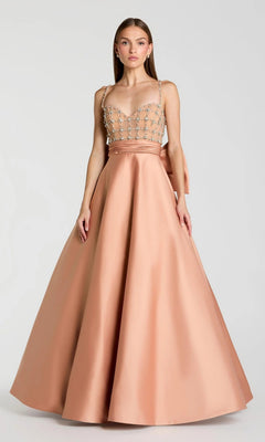 A woman wearing the Long Formal Dress: Mac Duggal 21242, a sleeveless dusty rose satin ballgown featuring a beaded sheer bodice and a full skirt, stands against a plain light background.