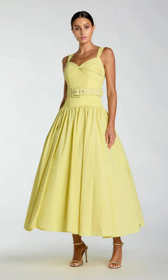 A woman wearing the Tea-Length Party Dress: Mac Duggal 21251—a yellow sleeveless dress with a belted waist and flared skirt—paired with strappy heels, stands against a plain background.