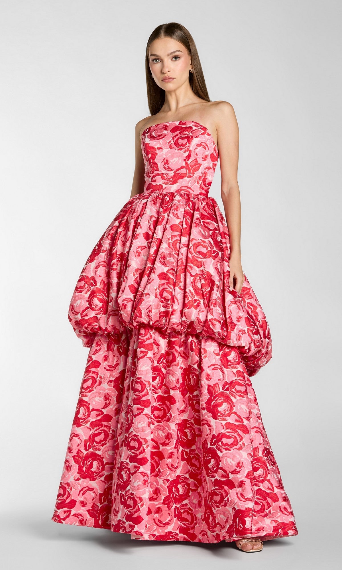 A woman wearing the Mac Duggal 21254 Long Formal Dress in Pink Multi, featuring a strapless design, floral pattern, voluminous bubble skirt, and floor-length hem reminiscent of Mac Duggal’s signature style, stands against a plain background.