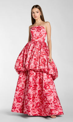 A woman wearing the Mac Duggal 21254 Long Formal Dress in Pink Multi, featuring a strapless design, floral pattern, voluminous bubble skirt, and floor-length hem reminiscent of Mac Duggal’s signature style, stands against a plain background.