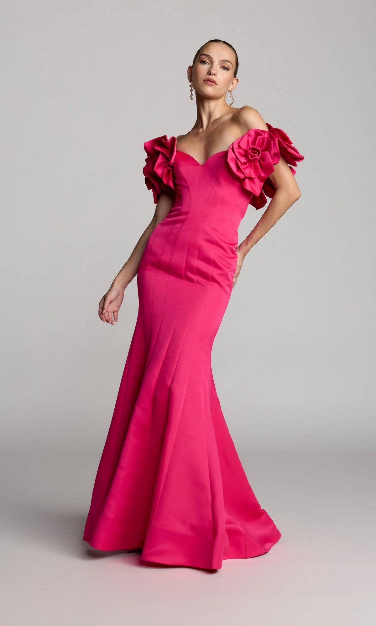 A woman models the Long Formal Dress: Mac Duggal 21263 in hot pink, featuring off-the-shoulder floral sleeves, against a plain gray background.