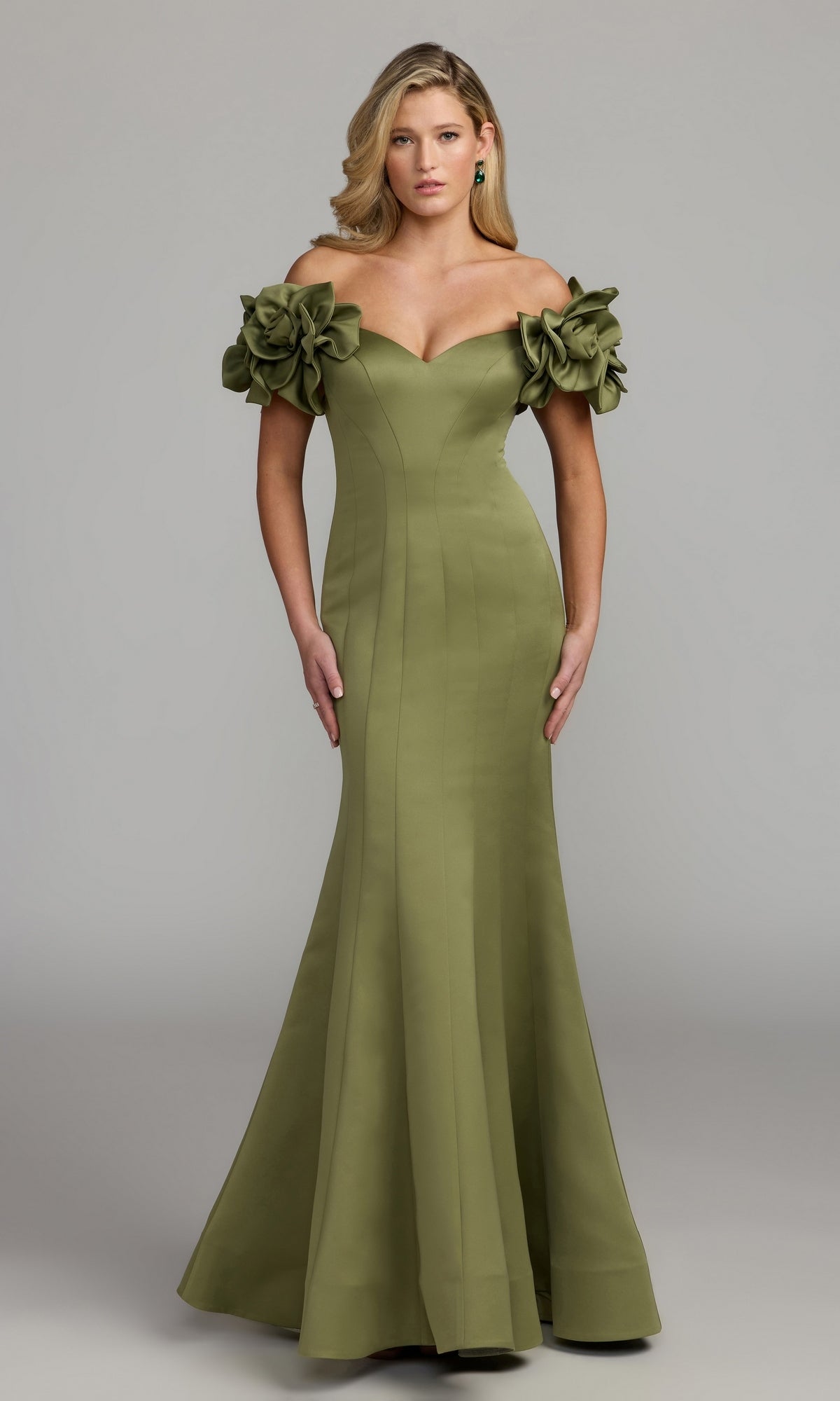 A woman in the Mac Duggal 21263 long formal dress in Pear, featuring an off-the-shoulder design with large floral accents on the sleeves, stands against a plain gray background.
