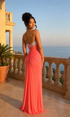 A woman in the La Femme Dress 21275, a strapless formal gown with coral hues, stands on a balcony overlooking the sea, framed by stone balustrades and a potted palm.