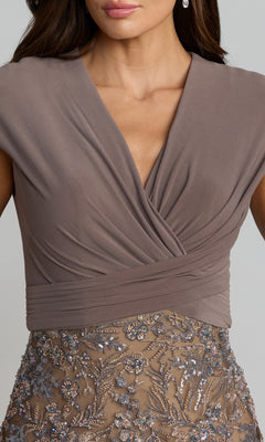 A woman wearing the Mac Duggal 21291 Long Formal Dress in mauve, featuring a wrapped V-neck top and an embroidered floral sequin skirt, shown from mid-face to upper thigh.