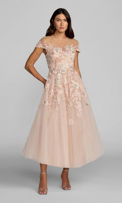 A woman wearing the Mac Duggal 21296 Tea-Length Party Dress in Blush Multi, featuring an off-the-shoulder neckline, intricate floral embroidery, and an elegant A-line tulle skirt, stands with her arms relaxed and gazes forward.