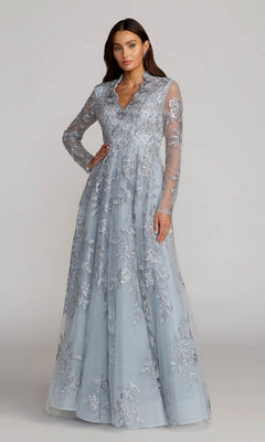A woman stands wearing the Mac Duggal 21307 long formal dress in slate blue, featuring sheer long sleeves and delicate floral-beaded embroidery, posing against a plain background.