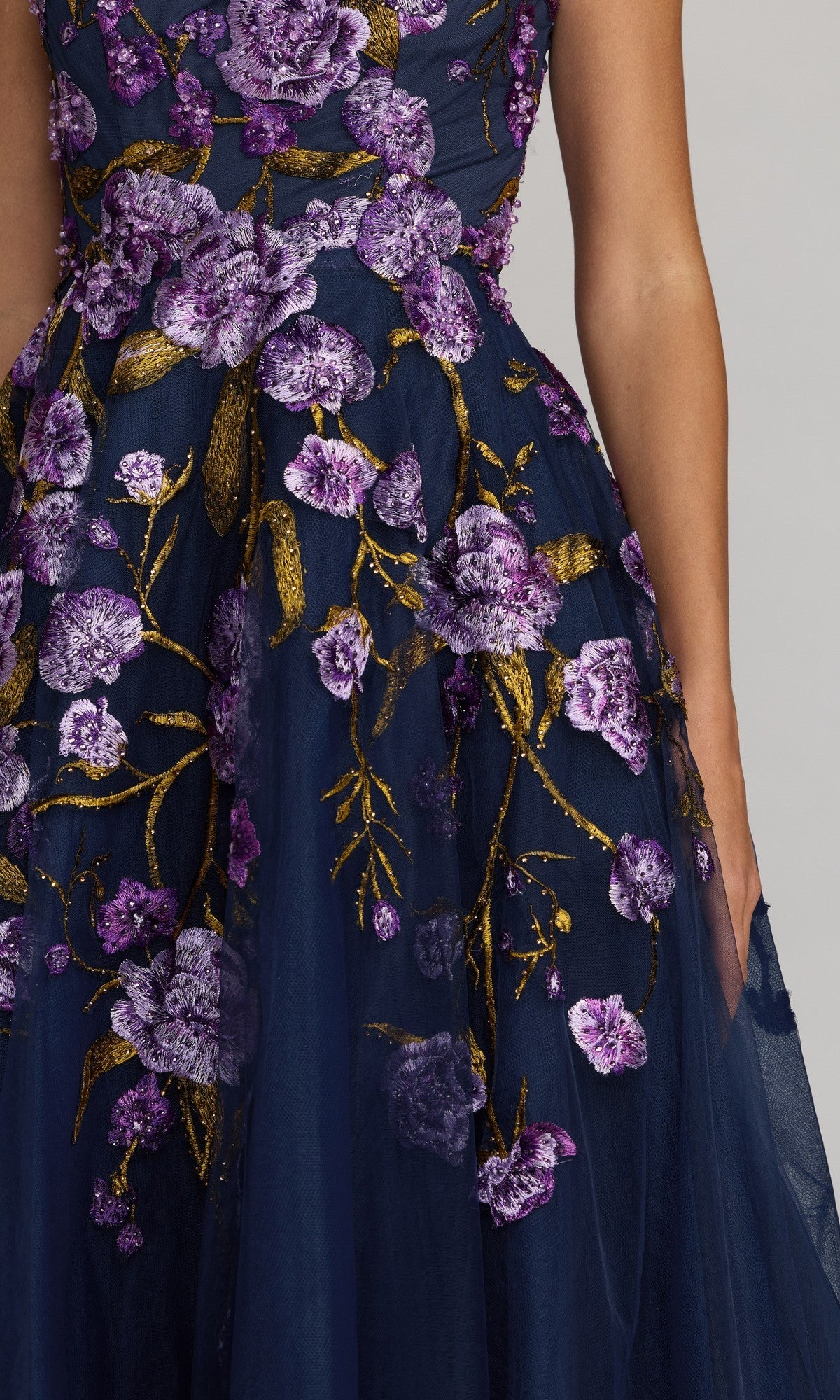 A person wearing the Mac Duggal 21358 ankle-length party dress in navy blue with purple and gold floral embroidery, shown from shoulder to mid-thigh against a neutral background.