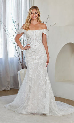 A woman smiles at the camera indoors, wearing the Amelia Couture 2153 long prom dress—a fitted off-the-shoulder white lace gown with a flared hem.