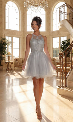 A woman wears the Beaded Embroidered Lace Short Babydoll Party Dress—a light gray, sleeveless homecoming dress with an embroidered bodice—in a spacious, elegant room with large arched windows and a curved staircase.