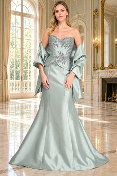 A woman wears the light green Long Formal Dress: Amelia Couture 2162, featuring a strapless bodice with silver floral embroidery and a matching shawl draped over her arms.