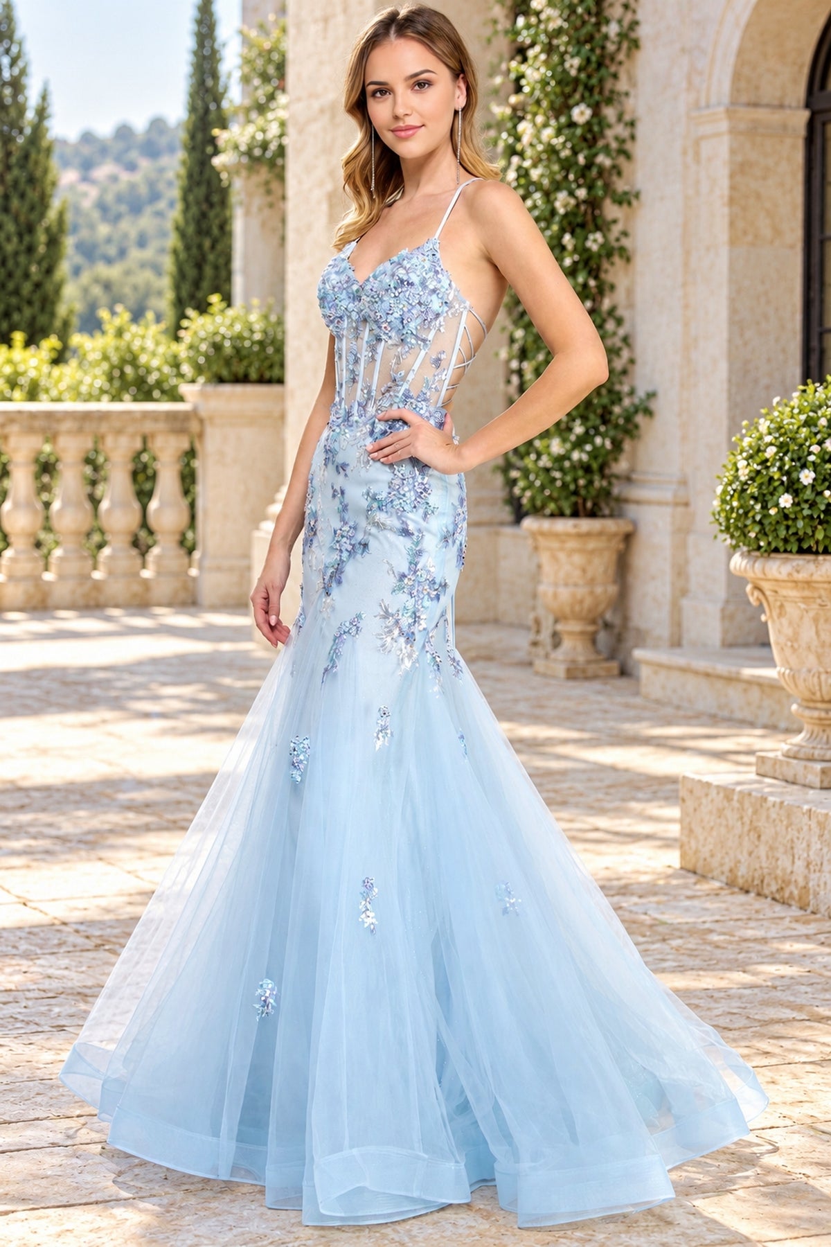 Amelia Couture 2164 light blue, floor-length mermaid prom dress with spaghetti straps, a sheer corset-style bodice, and sequin flower appliques.