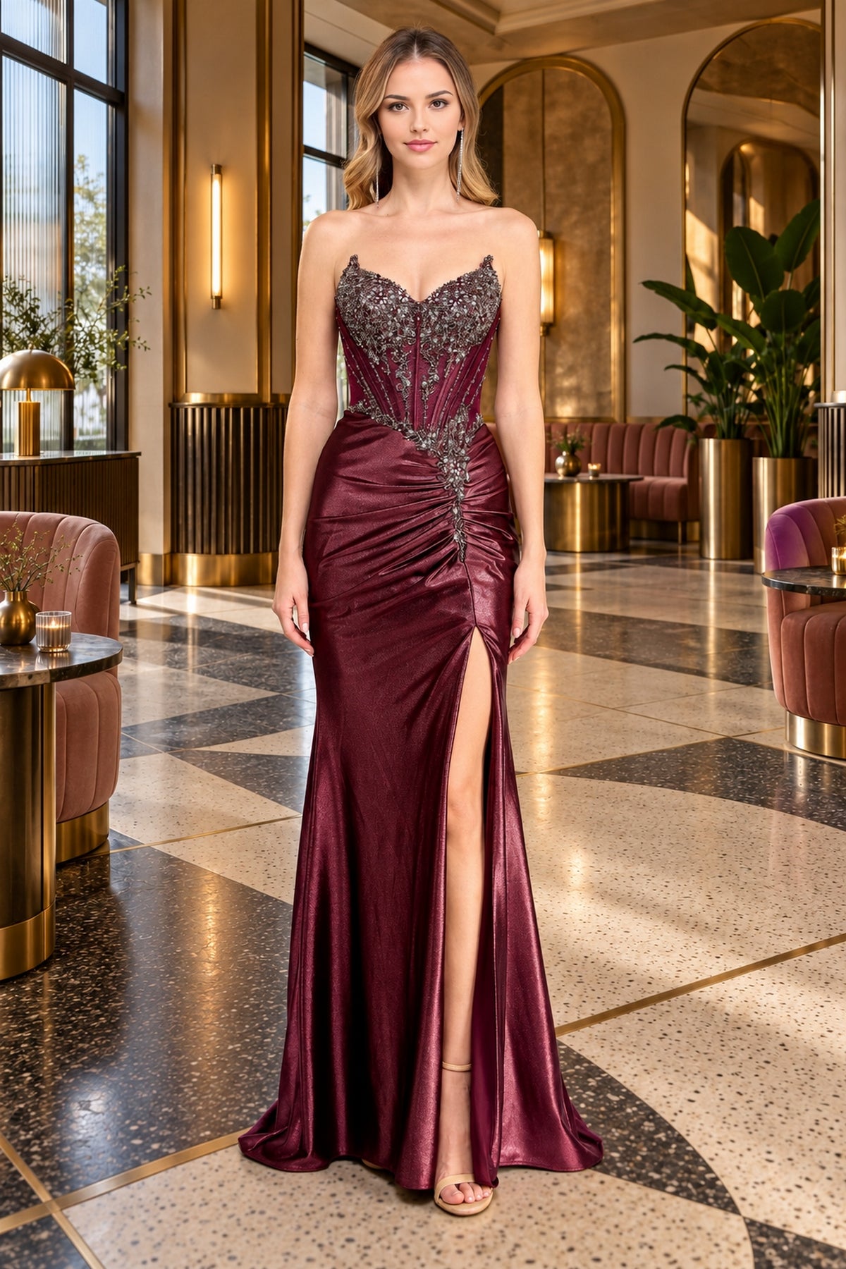 A woman wears a deep burgundy Long Prom Dress: Amelia Couture 2166, a strapless, floor-length gown featuring a beaded corset bodice and a high side slit.