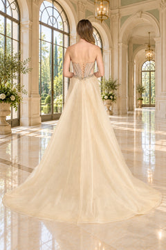 Back view of the Long Prom Dress: Amelia Couture 2172, a champagne, strapless floor-length gown with a corset-style bodice and a full tulle skirt in a formal hall.