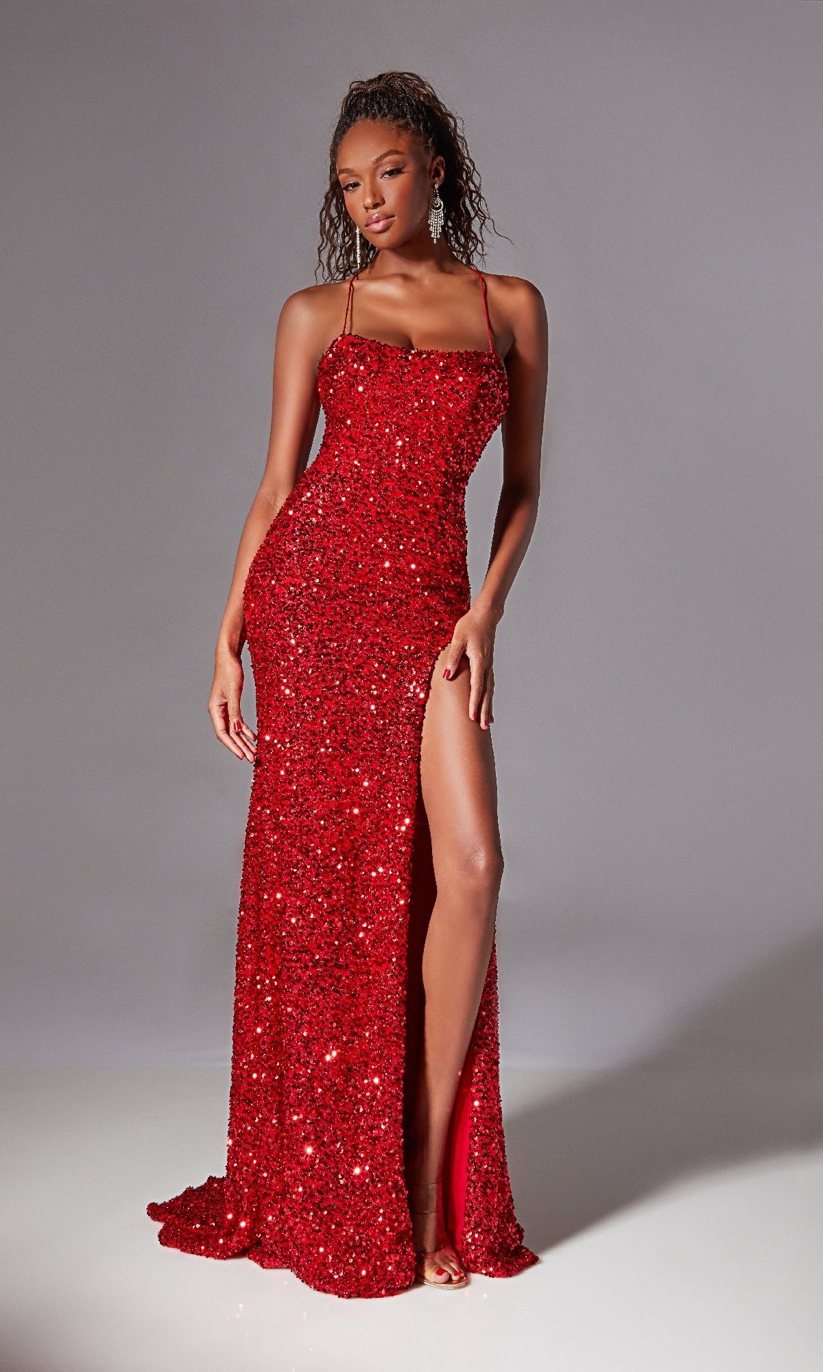 A woman models the Aerie Couture 217 Backless Long Sequin Prom Dress, a form-fitting gown with thin straps and a high slit, standing against a plain gray background.