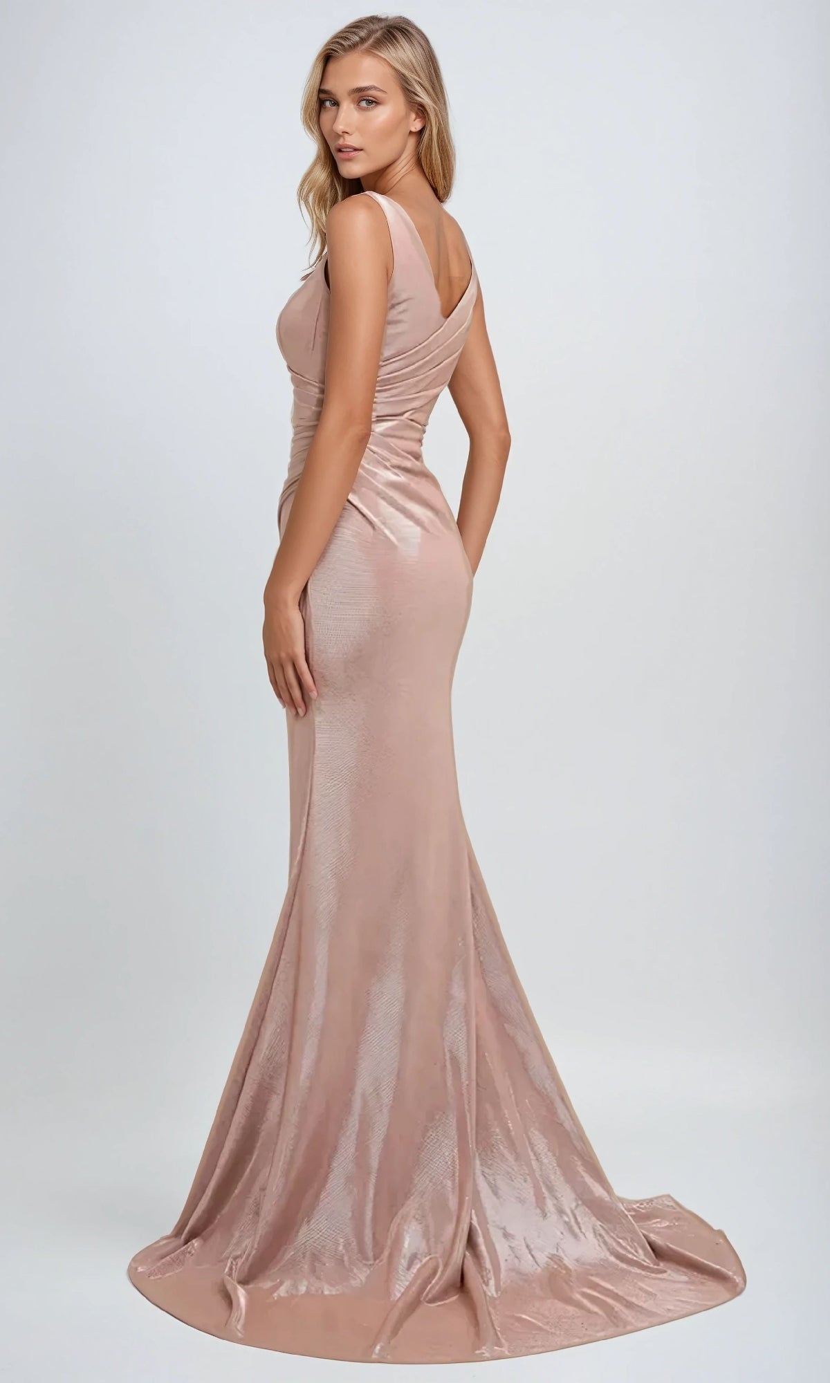 A woman poses against a plain light background in the Juliet 218 long prom dress—a fitted, sleeveless, rose gold metallic gown with a faux-wrap bodice and slight train.