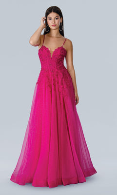 A woman models the Stella Couture 22027—a bright pink, floor-length A-line prom dress with thin straps, lace-embroidered bodice, floral appliqués, and a full tulle skirt—against a plain light gray background.