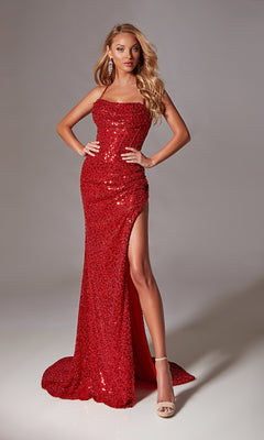 A woman poses against a plain gray background in the Draped Long Sequin Prom Dress: Aerie Couture 220—a sleeveless, floor-length red gown with a high slit, exuding stunning evening elegance with one hand on her hip.