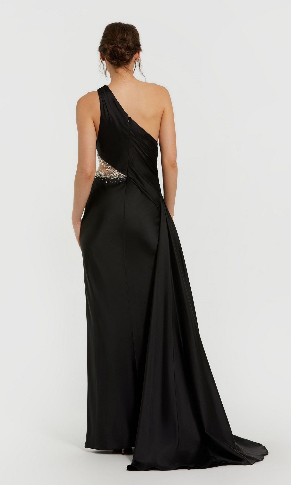 A woman wears the Mac Duggal 2210 Cut-Out One-Shoulder Formal Dress, featuring a side cutout and draped train, shown from the back.