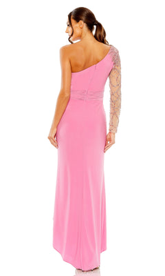 A woman stands with her back to the camera in a fitted pink Long Formal Dress 2215 by Mac Duggal, featuring a one-shoulder design and a sheer, beaded long sleeve.