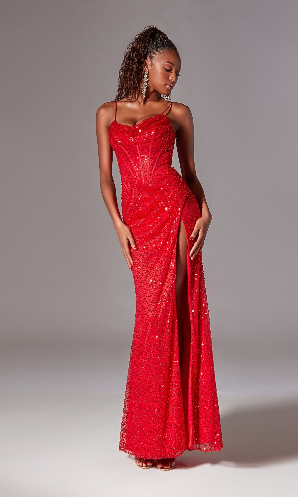 A woman models the Corset Long Sequin Prom Dress: Aerie Couture 221, featuring spaghetti straps, a corset-style bodice, and a high slit, against a plain backdrop.