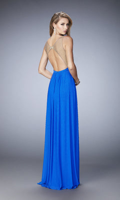 Woman wearing the La Femme 22238 long prom dress in royal blue with sheer straps and open back, standing and looking over her shoulder against a plain gray background.