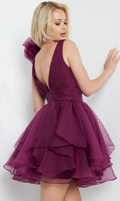 A woman models the Jovani Rosette-Shoulder Short Party Dress 22779, featuring a sleeveless, deep V-back layered plum design, as she poses with her back slightly turned against a plain white background.