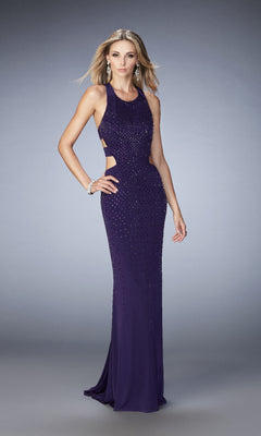 A woman models the La Femme 22287, a sleeveless, floor-length prom dress with side cutouts and rhinestone beading, accessorized with earrings and a bracelet against a plain background.