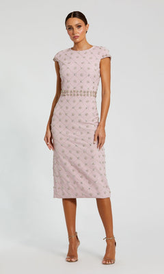 A woman wears the Mauve Pink Wedding Guest Dress: Mac Duggal 2234, a fitted midi with short sleeves, geometric beading, an embellished waistband, and strappy nude heels—perfectly elegant for a wedding guest.