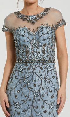 Woman wearing the Mac Duggal 2239 Beaded Long Blue Formal Dress, featuring a sheer neckline, detailed floral beadwork, embroidery, and cap sleeves—a stunning gown for any formal occasion.