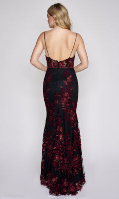 A woman faces away, modeling the Nina Canacci 2240, a black floor-length formal dress with red floral embroidery, thin straps, an open back, and a subtle mermaid silhouette.