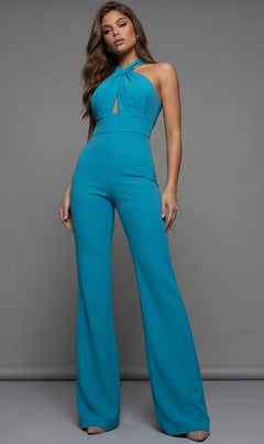 A woman poses against a plain gray background wearing the Jovani 22542 long jumpsuit, featuring a teal halter neckline and wide-leg pants.