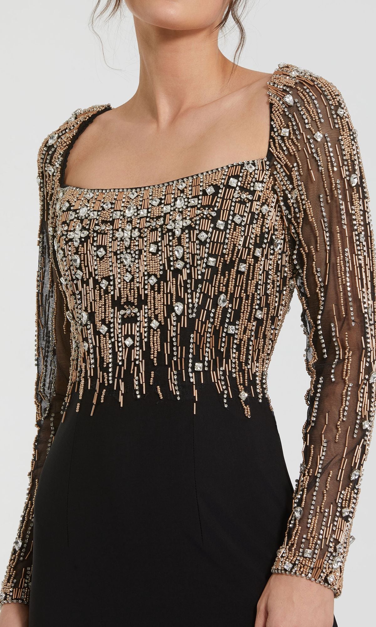 A woman wears the Mac Duggal 2256 Long Sleeve Long Formal Dress, featuring sheer sleeves and intricate gold and silver bead embellishments on the bodice and arms.