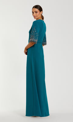 A woman models the Mac Duggal 2270 Short Sleeve Sleek Formal Dress in teal, featuring beaded short sleeves, as she poses against a plain white background.