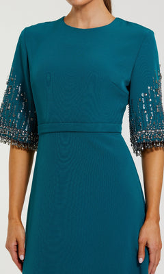 A woman wears the Short Sleeve Sleek Formal Dress: Mac Duggal 2270 in teal, featuring embellished short sleeves with bead and sequin details; her head is not visible.