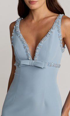 Woman in a sleeveless light blue Mac Duggal 2276 V-Neck Midi Wedding Guest Dress, featuring pearl and floral embellishments, bow waist, and deep V-neckline.