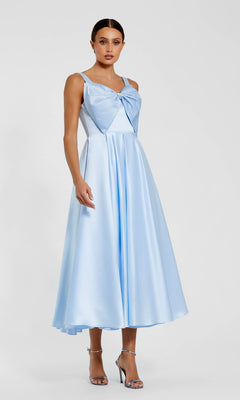 Woman wearing the Mac Duggal 2288 Midi Wedding Guest Dress in powder blue satin with a sleeveless A-line silhouette and bow chest detail, paired with silver open-toe heels—a chic choice for any wedding guest.